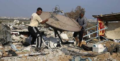 Hombres palestinos salvan una antena por sat&eacute;lite de las ruinas de su casa en Gaza. 