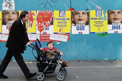 Un parisiense pasea a su hijo delante de carteles a favor del <i>sí </i>y del <i>no</i> en el referéndum del próximo día 29.