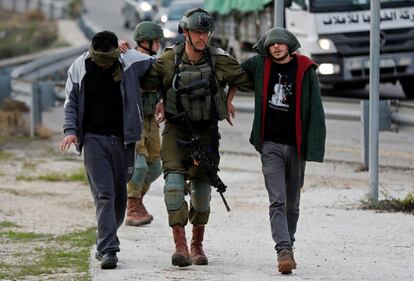 Un soldado israelí detiene a dos palestinos en Ras Karkar, cerca de Ramallah, en la Ribera Occidental ocupada por Israel.