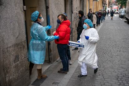 Personal sanitario atiende a personas haciendo cola para realizarse una PCR frente al centro de salud Universidad, en Malasaña, en Madrid, el pasado 20 de diciembre.