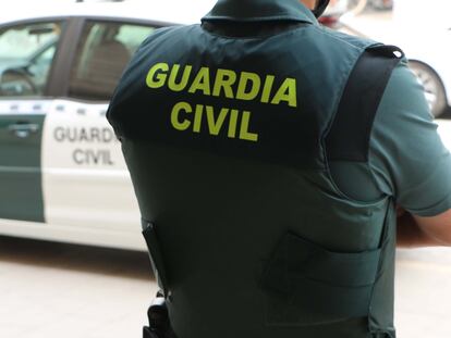 Un agente de la Guardia Civil, de espaldas, junto a un vehículo oficial, en una foto de archivo.