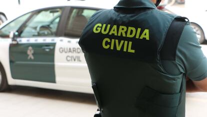 Un agente de la Guardia Civil, de espaldas, junto a un vehículo oficial, en una foto de archivo.