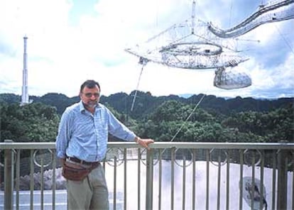 Daniel Altschuler, con el radiotelescopio de Arecibo al fondo. A la izquierda, una de las torres de hormigón de las que cuelgan las antenas centrales.