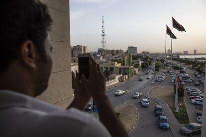 Un joven hace una foto en un mirador junto a la playa de Trípoli, desde el que se pueden ver dos enormes banderas frente al Ministerio de Asuntos Exteriores.