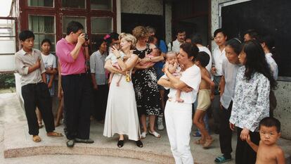 Seis familias belgas junto a los niños adoptados posan en la puerta del Centro Social de Acogida de Yueyang mientras los trabajadores y otros curiosos de la zona observan la escena, 1994.