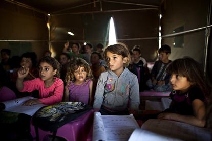 FILE - In this Tuesday, Aug. 11, 2015 file photo, Syrian refugee children attend a class at a makeshift school set up in a tent at an informal tented settlement near the Syrian border on the outskirts of Mafraq, Jordan. The U.N. agency for children says more than 80 percent of Syria's children have been harmed by the five-year-old conflict, including growing numbers forced to work, join armed groups or marry young because of widening poverty. (AP Photo/Muhammed Muheisen, File)