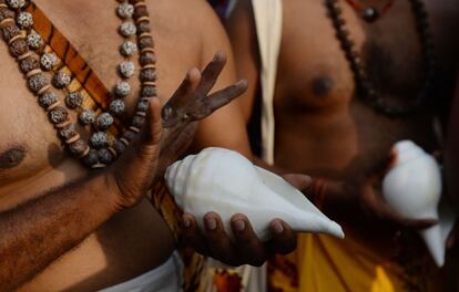 Devotos hindúes sujetan caracolas durante un festival en honor al dios Kapaleeswar en Chennai (India).
