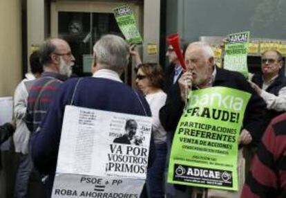 Un grupo de personas protesta a las puertas de una oficina de Bankia, en la madrileña calle de Gran Vía. Adicae ha animado a sus asociados a que participen hoy en la campaña "Toque a Bankia", una acción reivindicativa en la que está previsto que "miles de sucursales" de la entidad reciban la visita "incómoda" de las víctimas del fraude de las participaciones preferentes y deuda subordinada.