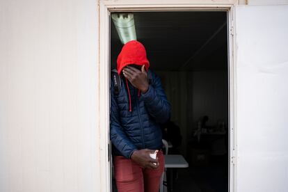 Bacary Camará, 35 años, procedente de Senegal se tapa la cara en la puerta de la cafetería habilitada en el exterior del albergue temporal instalado por el Ayuntamiento de Níjar (Almería) tras el desalojo del campamento el Walili.