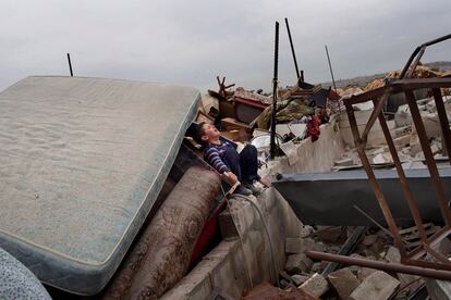 Un niño llora sobre la ruinas del edificio derribado.