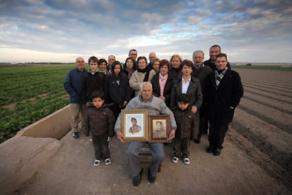 Matías Gimeno Orts holds a photo of himself and another of Juan Bautista García Sales (r). Surrounding him are members of Bautista's family.