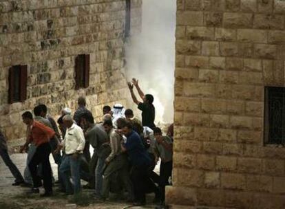 Varios palestinos corren para protegerse de los gases lanzados por la policía israelí, ayer en Cisjordania.