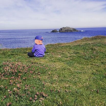 Un niño escucha el bar en una pradera cercana a un acantilado.