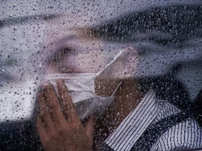 Un hombre con mascarilla en un automóvil durante un día lluvioso en Shanghái (China).