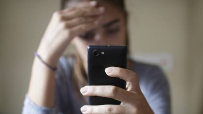 Una mujer observa su teléfono móvil.