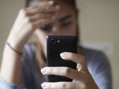 Una mujer observa su teléfono móvil.