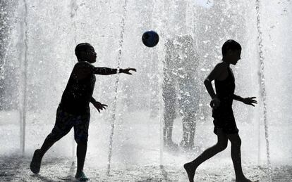 Dos niños juegan en una fuente durante un día caluroso en Fráncfort (Alemania).
