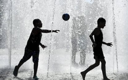 Dos niños juegan en una fuente durante un día caluroso en Fráncfort (Alemania).