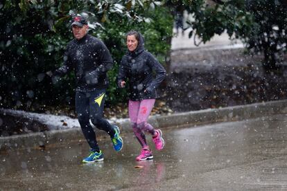 Una pareja entrena bajo la nieve, en el Parque del Retiro de Madrid.