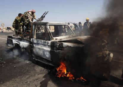 Rebeldes libios tratan de salvar el armamento de un vehículo de las fuerzas de Gadafi alcanzado por un bombardeo de la OTAN a las afueras de Brega.