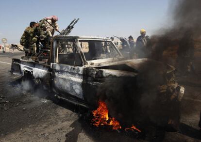 Rebeldes libios tratan de salvar el armamento de un vehículo de las fuerzas de Gadafi alcanzado por un bombardeo de la OTAN a las afueras de Brega.