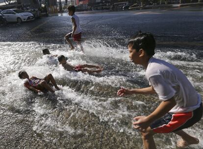 Niños ríen y juegan en el agua tras la rotura de una cañería en Manila (Filipinas).