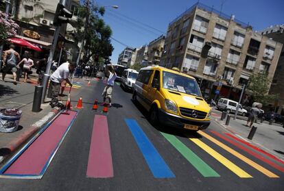 Un mini bus pasa por un paso de peatones en cuya decoración trabajan operarios municipales con motivo del desfile anual del orgullo gay en Tel Aviv (Israel).