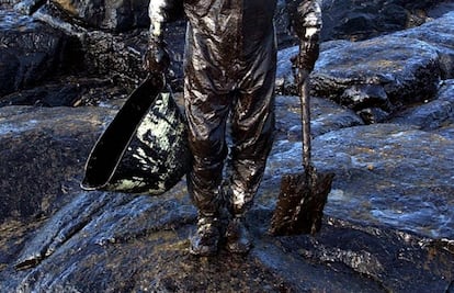 Un voluntario, con el traje de trabajo impregnado de fuel, recoge con sus manos vertidos procedentes del petrolero Prestige en la playa de La Pedriña, en la localidad coruñesa de Muxia, el 6 de diciembre de 2002. 