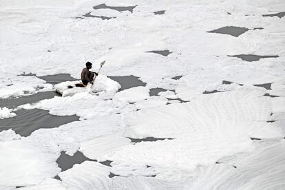 Un hombre rema en su balsa mientras recolecta materiales reciclables en las aguas del río Yamuna cubiertas con espuma contaminada en Nueva Delhi (India)