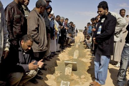 Familiares de las víctimas de los ataques aéreos del régimen sobre Brega rezan durante el funeral, celebrado ayer en Ajdabiya.