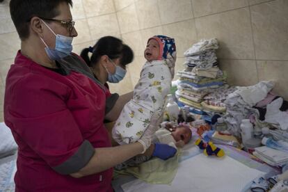 Dos mujeres cambian el pañal a los bebés de una guardería de Kiev, este sábado.