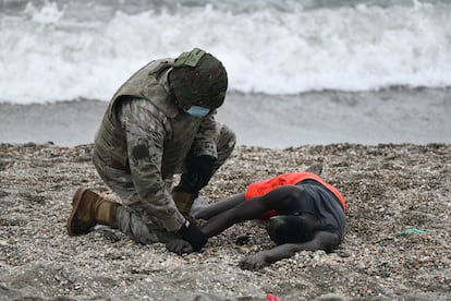 Un militar atiende a una persona tumbada en la orilla de la playa de Ceuta tras haber llegado a nado desde Marruecos, el pasado martes.