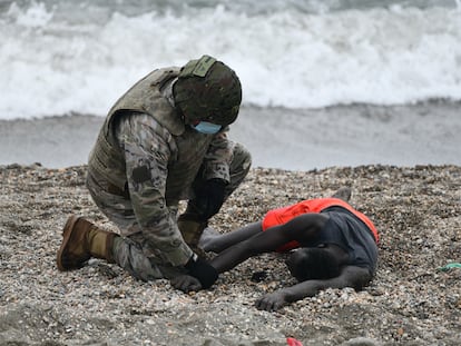 Un militar atiende a una persona tumbada en la orilla de la playa de Ceuta tras haber llegado a nado desde Marruecos, el pasado martes.