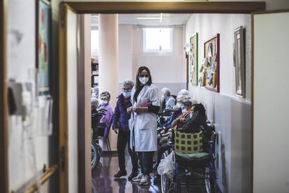 Los mayores no pueden bajar al pueblo a tomarse un café y charlar con sus conocidos. Como mucho, pasean por la orilla del río Miño porque “es una zona amplia y sin aglomeraciones”, explica la directora del centro. Una encuesta realizada hace un par de meses entre los usuarios reveló que esta es la actividad que más añoran. En la imagen, una trabajadora acompaña a una residente a una evaluación, en una sala con varios internos.