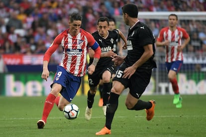 El delantero español del Atlético de Madrid Fernando Torres se lleva el balón ante los jugadores del Eibar Paulo Rodrigues y José Ángel.