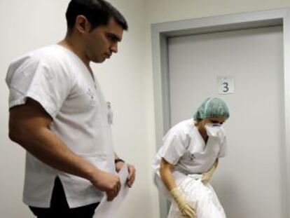 Dos auxiliares del Hospital La Fe (Valencia) se colocan los trajes de protección en presencia de un instructor.