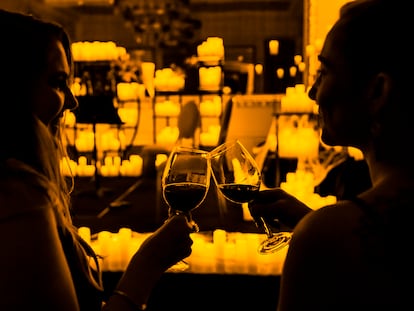 Dos personas disfrutan de unos vinos en un concierto de música clásica a la luz de las velas.