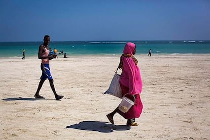 Una mujer pasea en la playa de Liido. De fondo, las costas que antes surcaban los piratas; hoy muchos han recuperado su oficio de pescador.