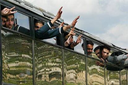 Palestinos liberados saludan desde el autobús tras cruzar el control fronterizo de Hebrón.