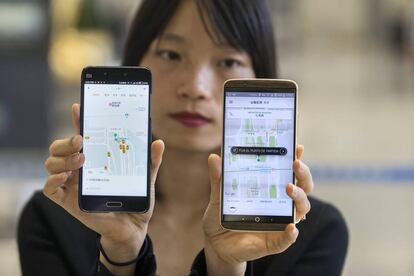 Una mujer china muestra las aplicaciones de Didi y de Uber en China