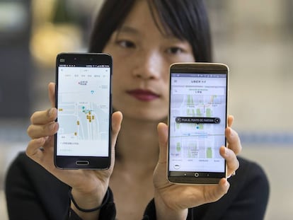 Una mujer china muestra las aplicaciones de Didi y de Uber en China
