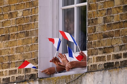 Varios espectadores ondean la bandera tricolor francesa mientras el rey Carlos III del Reino Unido, la reina Camila, el presidente de Francia, Emmanuel Macron, y su esposa Brigitte pasan en carruaje por Windsor.