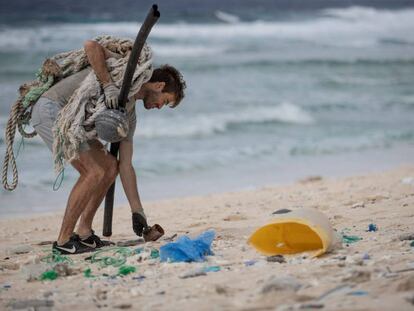 Un hombre, miembro de un grupo de voluntarios medioambientalistas, recoge residuos en una playa de la isla deshabitada de Henderson, en el sur del Océano Pacífico.