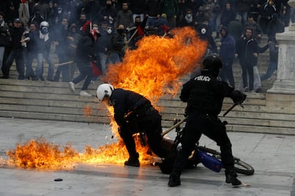 Un policía trata de zafarse de las llamas tras haber recibido el lanzamiento de un cóctel molotov por parte de manifestantes en Atenas. Grecia vive hoy otro día de huelga genera contra las medidas de austeridad económica del Gobierno.