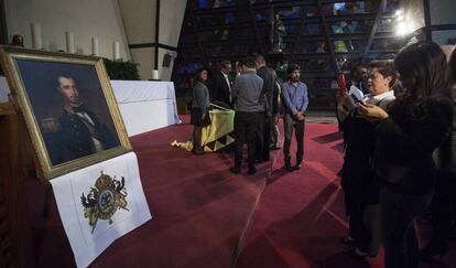 Un grupo de asistentes a la misa en conmemoración de la muerte de Maximiliano de Habsburgo toma fotos a su retrato.