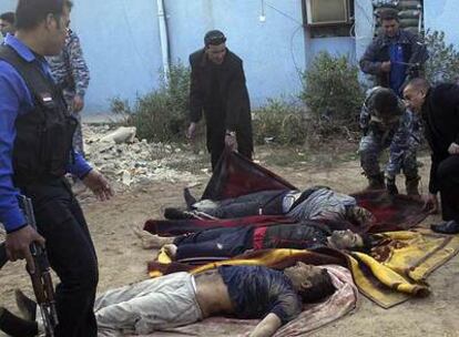 Policías iraquíes colocan sobre mantas los cuerpos de tres de los prisioneros muertos.