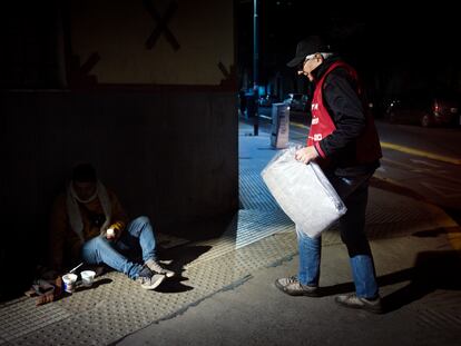 Un voluntario de una organización social entrega una manta a un hombre en siutación de calle, el 2 de junio en Buenos Aires.