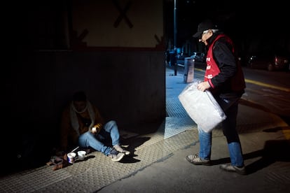 Un voluntario de una organización social entrega una manta a un hombre en siutación de calle, el 2 de junio en Buenos Aires.