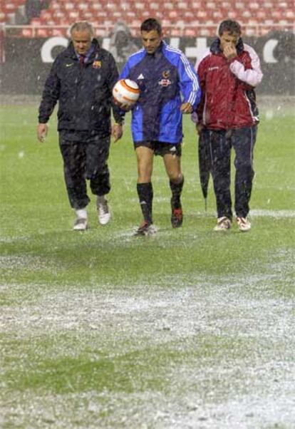 Teixeira (centro), árbitro del Sevilla-Barça, inspecciona el campo.