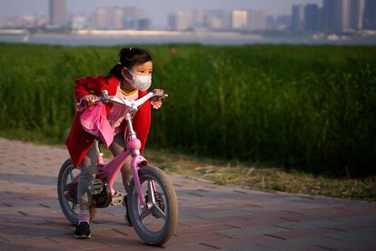 Uma menina anda de bicicleta num parque de Wuhan.